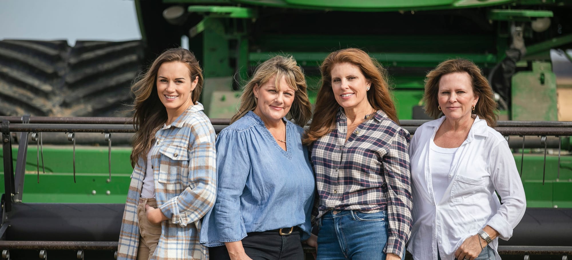 The four Kennedy sisters - Meryl, Chantel, Felicity and Patchez - standing in front of a green combine harvester on the family rice farm