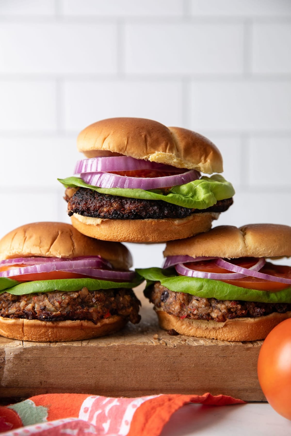 Three stacked veggie burgers with lettuce and red onion