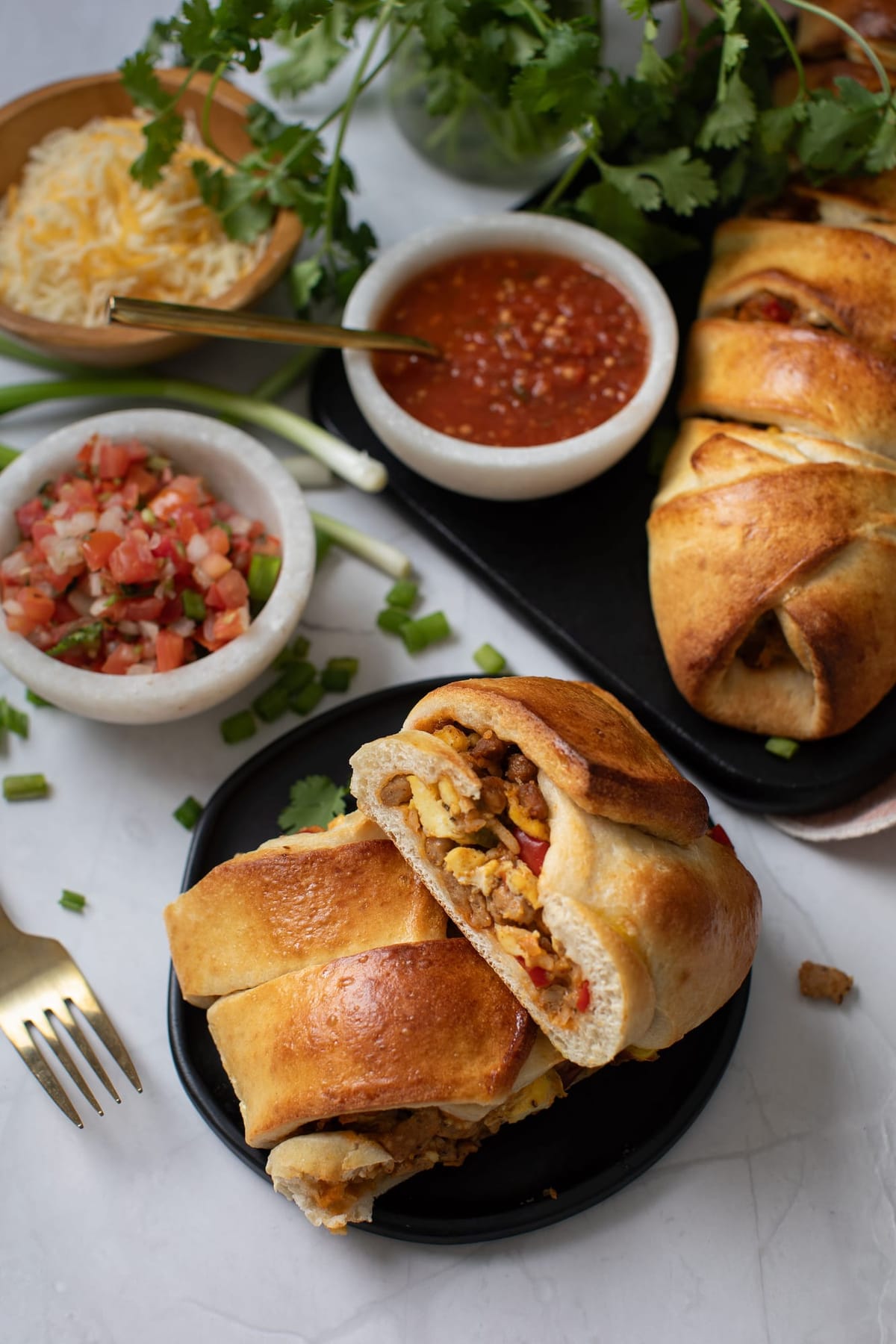 Savory pastry cut open, filled with egg and cheese, served with salsa