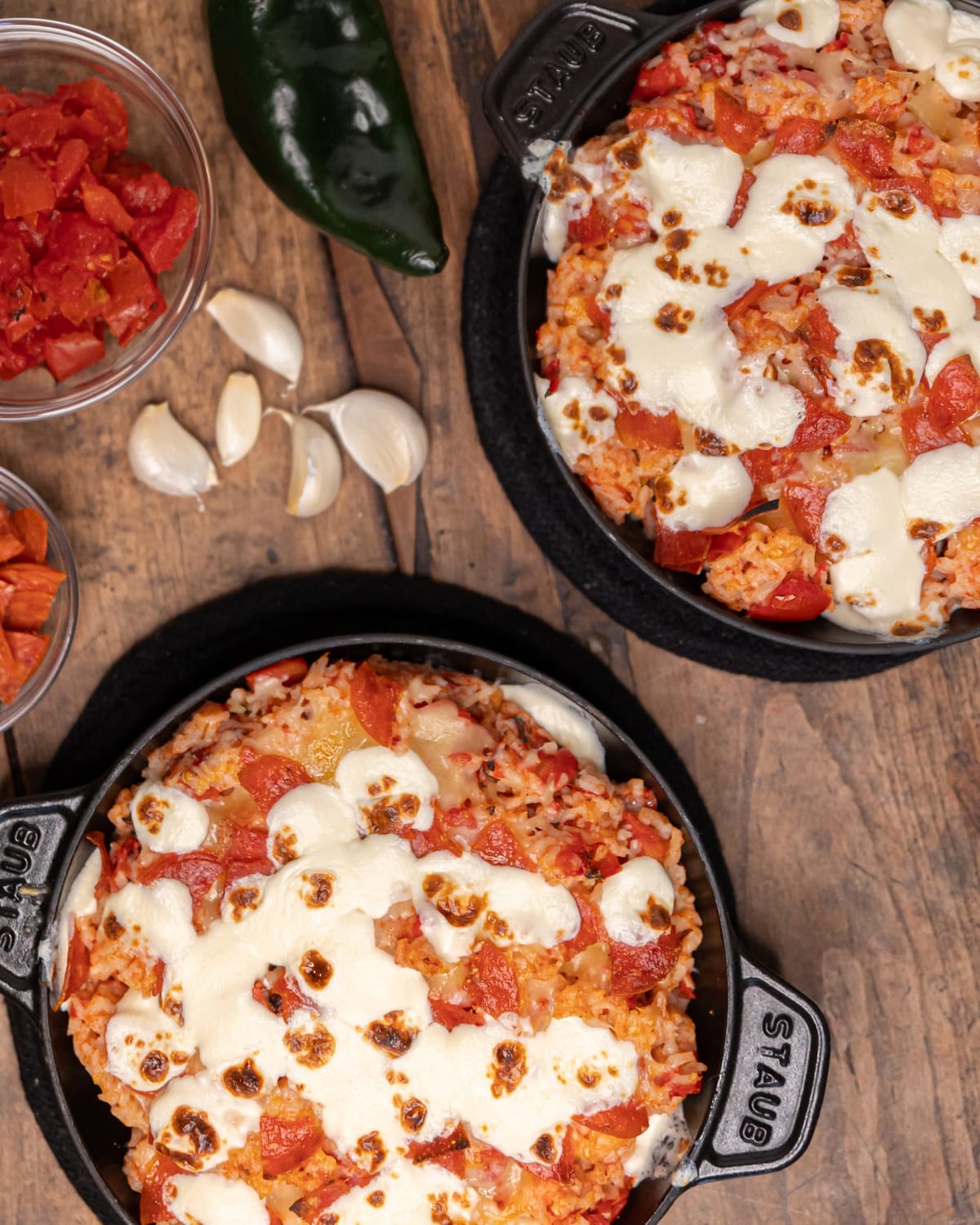 Baked cheesy tomato dishes in pans with garlic, pepper