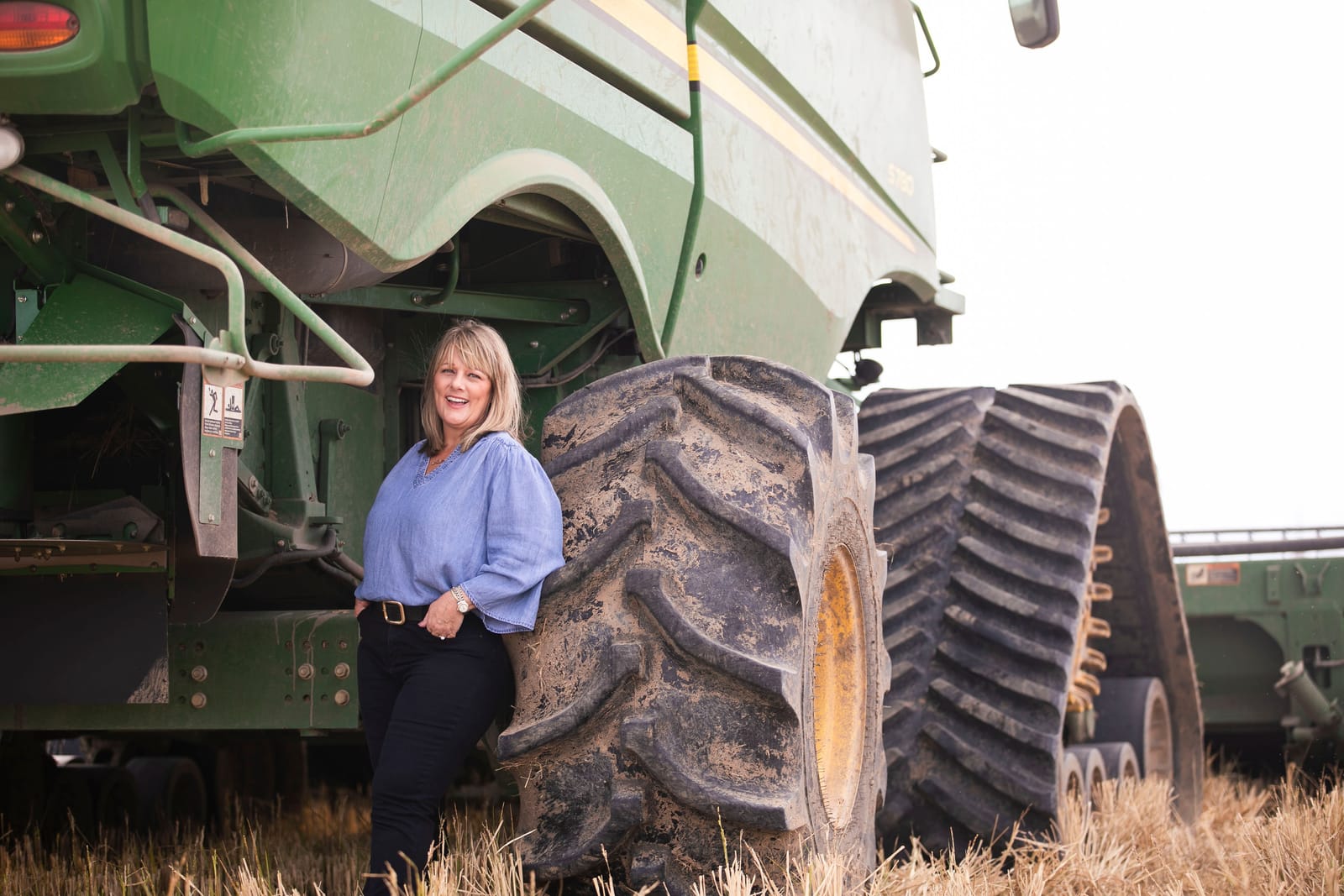 A 4 Sisters Rice farmer standing beside a green combine harvester in a Louisiana field at harvest