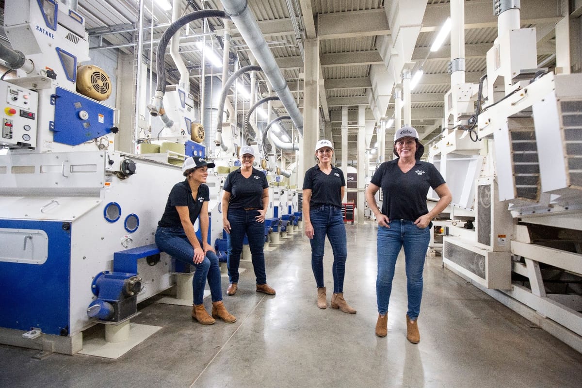 The four Kennedy sisters standing together among the milling machinery inside the 4 Sisters Rice plant